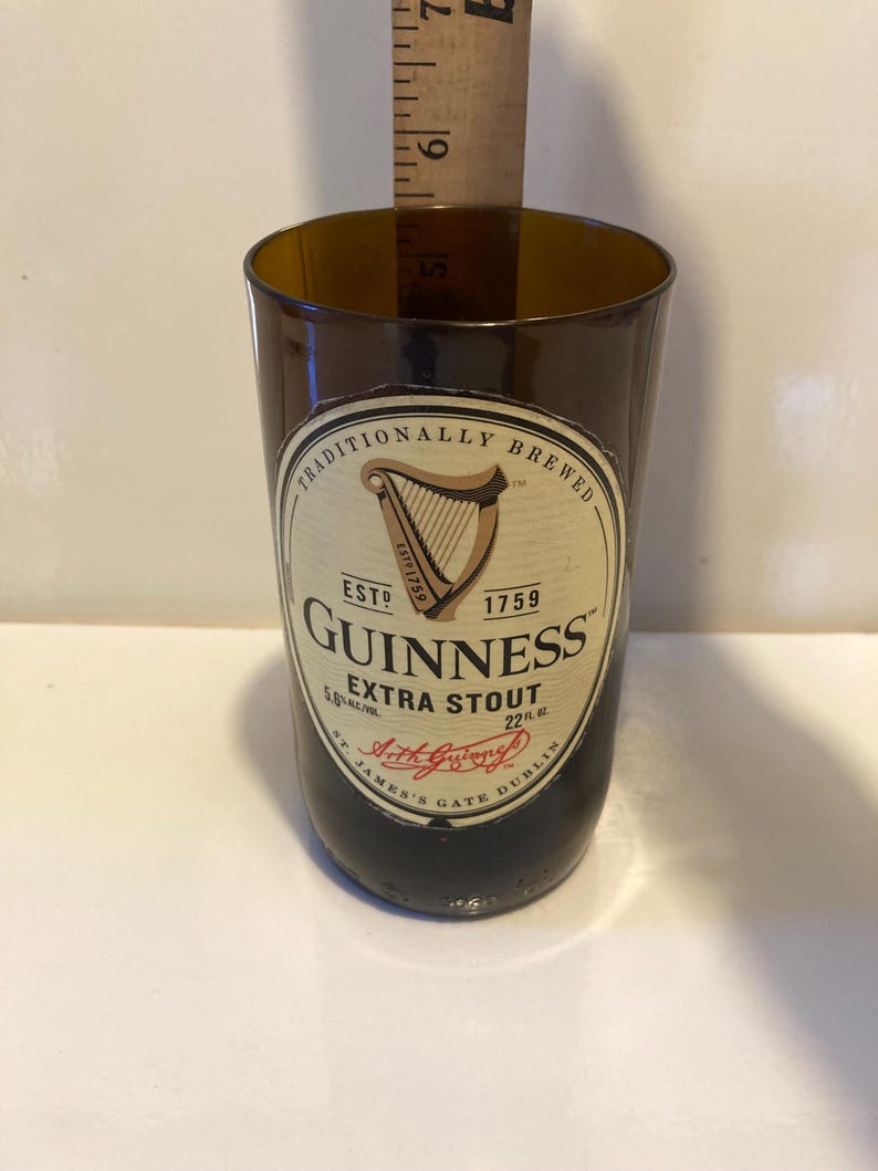 May include: A brown glass bottle with a label that reads "Traditionally Brewed" and "Guinness Extra Stout". The label also includes the Guinness harp logo and the text "Est. 1759".