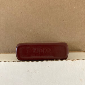 May include: A red Zippo lighter with the word "Zippo" embossed on the front.