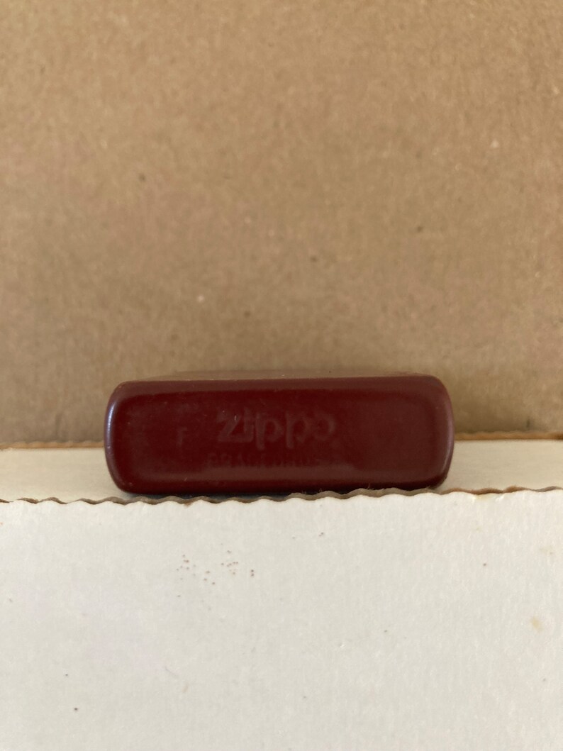 May include: A red Zippo lighter with the word "Zippo" embossed on the front.
