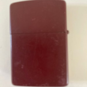 May include: A dark red lighter with a slightly worn finish.
