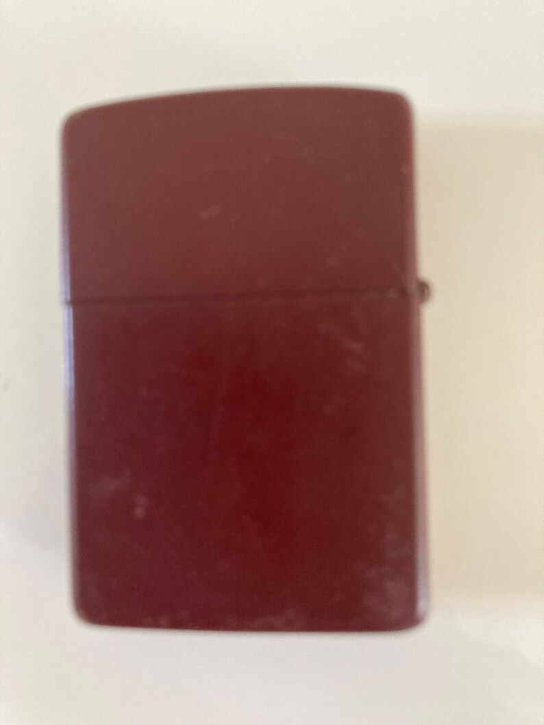 May include: A dark red lighter with a slightly worn finish.