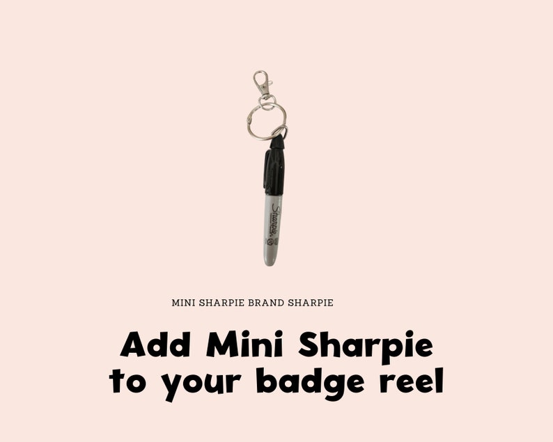 以下が含まれることがあります： シルバーのキーリングと留め金に取り付けられた黒いMini Sharpieマーカー。「Add Mini Sharpie to your badge reel」というテキストが太字の黒で表示されています。