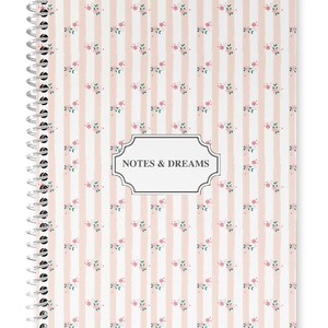May include: A pink and white spiral notebook with a floral pattern and the text "NOTES & DREAMS" on the front cover.
