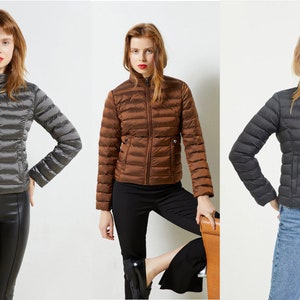 May include: Three puffer jackets in different colors: gray, brown, and black. Each jacket has a zipper closure and a stand-up collar.