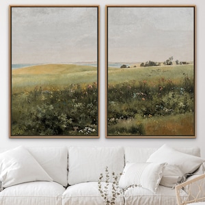 May include: Two framed landscape paintings depicting a field of wildflowers and a distant horizon. The paintings are in a muted color palette of greens, browns, and blues.