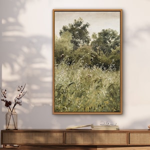May include: A framed painting of a landscape with green trees and tall grass in the foreground. The painting is set against a white wall with a wooden shelf below it.