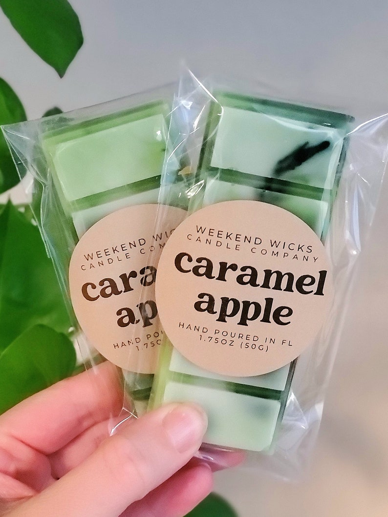 May include: Two packages of caramel apple scented wax melts. Each package contains five light green wax melt bars. The packages are sealed in clear plastic and have a round label with the text "Caramel Apple" and "Weekend Wicks Candle Company".