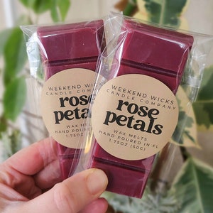 May include: Two wax melts in clear packaging, each with a burgundy colored wax block. The wax melts are labeled "Weekend Wicks Candle Company" and "rose petals" with the weight "1.75 oz (50g)".