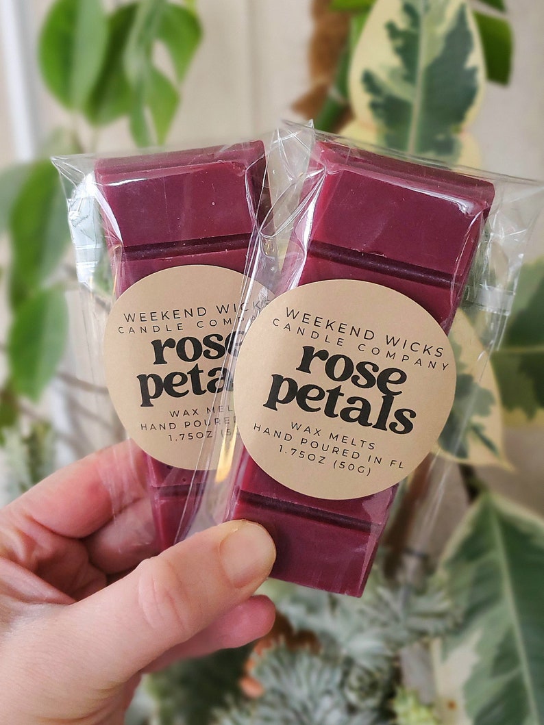 May include: Two wax melts in clear packaging, each with a burgundy colored wax block. The wax melts are labeled "Weekend Wicks Candle Company" and "rose petals" with the weight "1.75 oz (50g)".