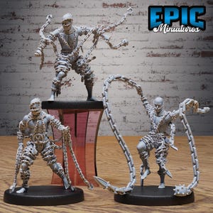 May include: Three gray miniature figures of chained characters. Each figure is posed differently, with chains wrapped around their bodies and extending outwards. The figures are on black bases, with the Epic Miniatures logo in the top right corner.