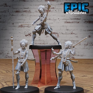 May include: Three grey painted miniature figurines of women with afro hairstyles. The figures are posed in different stances, holding various weapons and accessories. The figures are standing on black bases with a red and clear plastic stand in the centre.