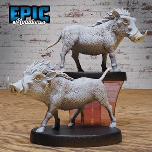 May include: Two grey painted miniature warthog figurines with detailed tusks and textured fur. The figurines are posed on black bases.