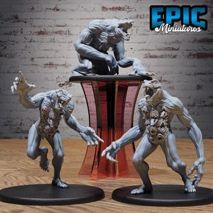 May include: Three grey monster miniatures featuring muscular humanoid forms with multiple mouths on their torsos and sharp teeth. One figure is crouched on a red pedestal, while two others stand on black circular bases. The text EPIC Miniatures is visible.