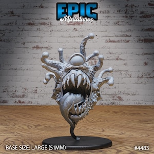 May include: A gray, detailed miniature of a beholder with multiple eyes and a large, open mouth. The miniature is on a black base and is labeled "EPIC Miniatures #4483". BASE SIZE: LARGE (51MM)