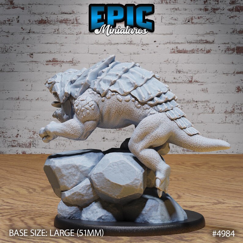 Pu&ograve; includere: Una miniatura grigia e dettagliata di una creatura rettile con una schiena spinosa, in piedi su una base rocciosa. La miniatura &egrave; di 51 mm e porta l'etichetta "EPIC Miniatures #4984".