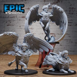 May include: Three grey unpainted resin miniature figurines of winged sphinx-like creatures. Each figure features a human-like head, large feathered wings, and a feline body with armor plating on the chest. The logo Epic Miniatures is visible.