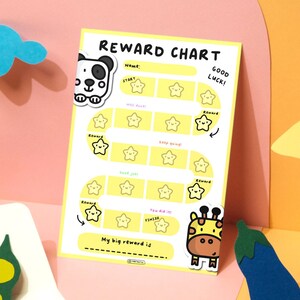 May include: A yellow reward chart with a path of star-shaped boxes. The chart includes the text "Reward Chart", "Good Luck!", and "My big reward is". Decorative panda and giraffe stickers are attached to the chart.