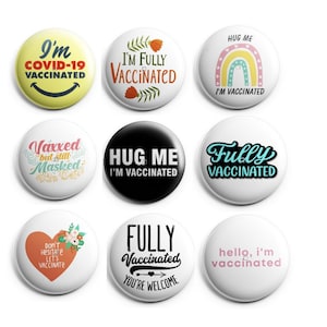Könnte beinhalten: Neun runde Knöpfe mit verschiedenen Designs und Texten zum Thema Impfung gegen COVID-19. Die Knöpfe zeigen Sätze wie "Ich bin vollständig geimpft", "Umarme mich, ich bin geimpft" und "Geimpft, aber immer noch maskiert".