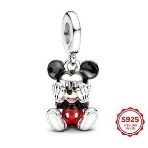 Könnte beinhalten: Ein silberner Charm-Anhänger mit einem sitzenden Mickey Mouse-Design. Der Charm hat schwarze Ohren, einen schwarzen Körper, rote Shorts und weiße Handschuhe und Schuhe. Der Charm ist mit "S925 Sterling Silver" gekennzeichnet.