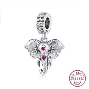 Könnte beinhalten: Ein silberner Elefanten-Charm mit dekorativem Design. Der Charm zeigt einen detaillierten Elefantenkopf mit rosa Edelsteinakzenten an Augen und Stirn. Der Charm hängt an einer silbernen Öse mit klaren Steinakzenten. Der Charm ist mit "925" und "Real Sterling Silver" gekennzeichnet.