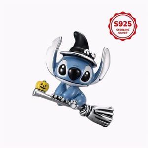 Pode incluir: Um berloque de prata esterlina apresentando um personagem azul usando um chapéu de bruxa preto, montado em uma vassoura e segurando uma pequena abóbora amarela. Inclui um emblema vermelho com o texto S925 STERLING SILVER.