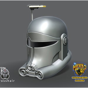 Pode incluir: Um capacete prateado com uma viseira preta e uma pequena antena retangular no topo. O capacete tem uma superfície texturizada e um design que se assemelha a uma máscara facial. O texto "Crosshair" é visível abaixo do capacete.
