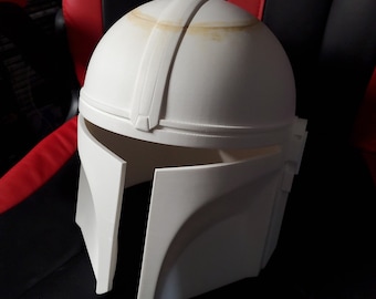 May include: A white plastic helmet with a raised design. The helmet has a rounded top and a visor that covers the eyes.