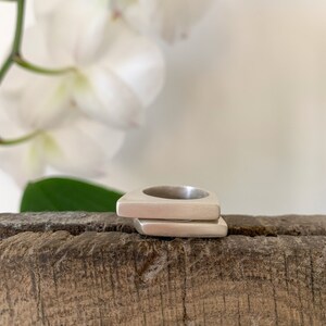 May include: Two silver rings stacked on top of each other. The rings are triangular in shape and have a smooth, polished finish.