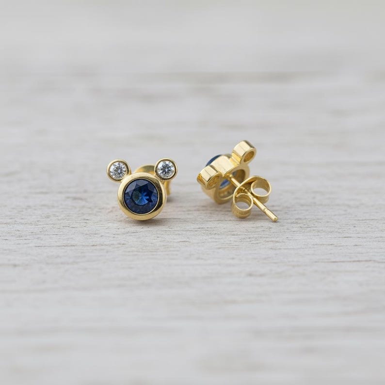 Cute mouse-inspired blue CZ earrings with gold plating and clear stones. Petite minimalist studs by JewelsMinimal for everyday charm.
 cute earrings, CZ studs, gold jewelry, minimal style, blue crystal earrings