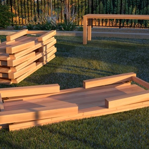 Puede incluir: Una mesa plegable de madera se está ensamblando parcialmente en un césped. La mesa está hecha de madera natural y tiene un diseño simple. La mesa está doblada por la mitad y las patas están extendidas.
