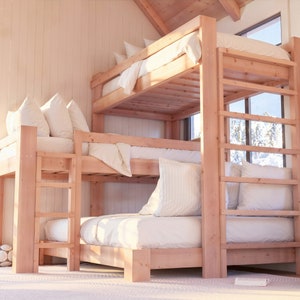 May include: A triple bunk bed made of natural wood with white bedding and pillows. The bed is in a room with a large window and a white wall.