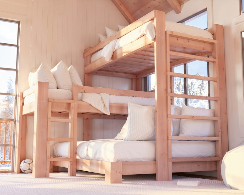 May include: A triple bunk bed made of natural wood with white bedding and pillows. The bed is in a room with a large window and a white wall.