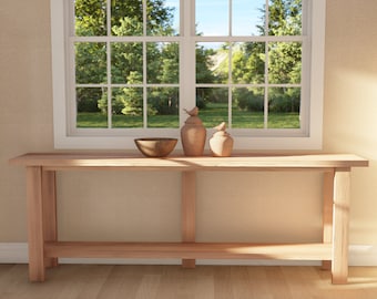 Op de afbeelding: Een houten consoletafel met een plank, met een bruine kom en twee decoratieve keramische vazen met vogelbeeldjes erop. De tafel staat voor een raam met uitzicht op een groene gazon en bomen.