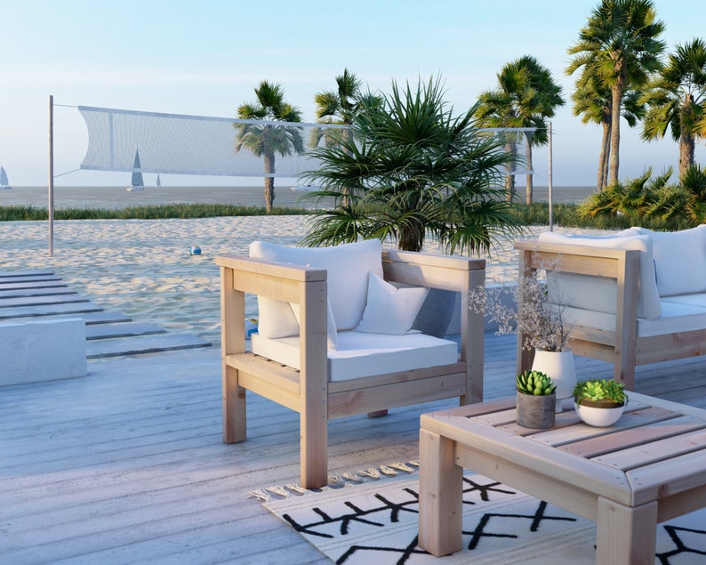 Puede incluir: Dos sillas de madera con cojines blancos y una mesa de caf&eacute; de madera a juego en una terraza de madera blanca con una playa de arena blanca y palmeras en el fondo.