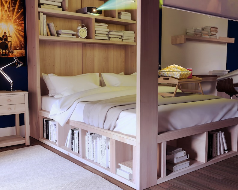 May include: A wooden bed frame with built-in shelves and storage compartments. The bed has a white duvet and pillows. A projector is mounted on the ceiling, projecting a movie onto the wall. A bowl of popcorn is on a small table next to the bed.