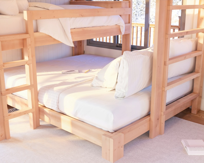 May include: A wooden bunk bed with a white mattress and white bedding on the top bunk. The bottom bunk has a white mattress and white bedding with a pillow on the bed. The bed is made of natural wood and has a ladder on the side.