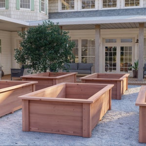 Op de afbeelding: Vijf houten verhoogde plantenbakken in een achtertuin. De bakken zijn gemaakt van natuurlijk cederhout en zijn in een verspringend patroon gerangschikt. De bakken zijn leeg en klaar om te planten.