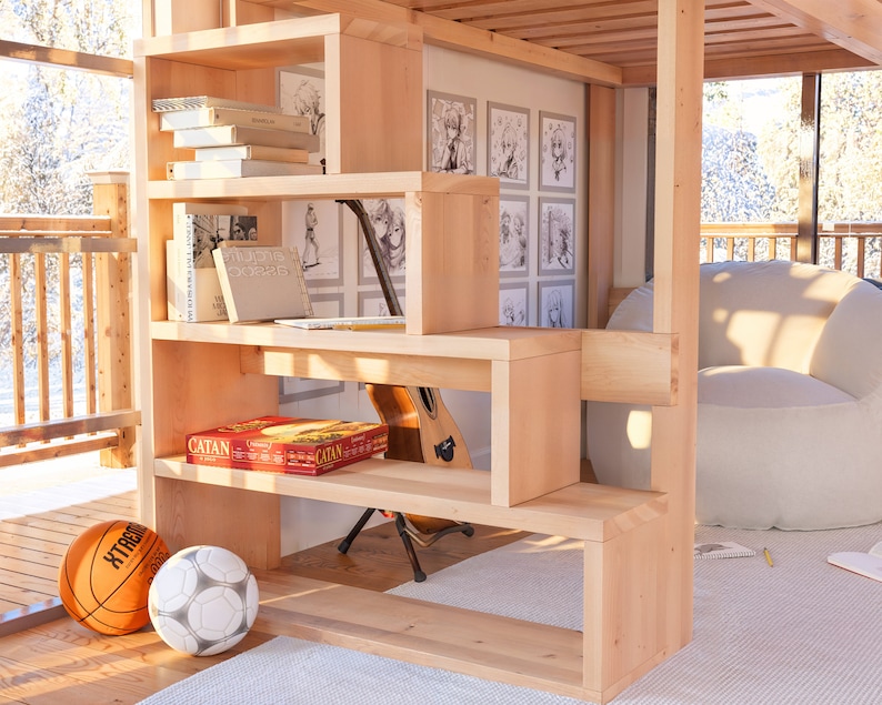 Puede incluir: Una estanter&iacute;a de madera con varios estantes, algunos de los cuales est&aacute;n abiertos y otros cerrados. Los estantes est&aacute;n llenos de libros, juegos y otros art&iacute;culos. Hay una guitarra apoyada en la estanter&iacute;a. La estanter&iacute;a est&aacute; en una habitaci&oacute;n con una pared blanca y una ventana grande. Hay un puf blanco en la habitaci&oacute;n.