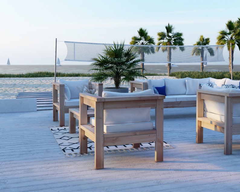 Puede incluir: Un conjunto de muebles de exterior de madera con cojines blancos. El conjunto incluye un sof&aacute;, dos sillones y una mesa de centro. Los muebles est&aacute;n en una terraza de madera con vistas a una playa y palmeras.