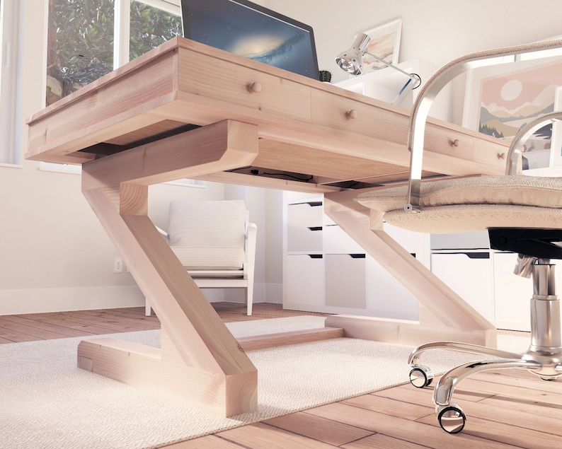 Puede incluir: Un escritorio de madera clara con una base en forma de Z y cajones. El escritorio est&aacute; en una habitaci&oacute;n con una silla blanca y una c&oacute;moda blanca.