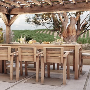 Op de afbeelding: Een houten eettafelset voor buiten met een rechthoekige tafel en zes stoelen. De tafel en stoelen zijn gemaakt van natuurlijk hout en hebben een rustieke afwerking. De set staat onder een houten pergola met lichtslingers. De achtergrond toont een wijngaard met een grote boom in het midden.