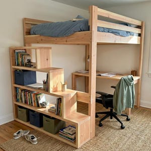 Peut inclure: Un lit mezzanine en bois avec des escaliers intégrés qui servent d'étagères. Le cadre du lit est en bois naturel, et les escaliers ont des étagères ouvertes remplies de livres et de bacs de rangement. Un bureau et une chaise sont positionnés sous le lit.