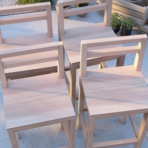 Puede incluir: Cuatro sillas de madera con un dise&ntilde;o sencillo, con respaldo de listones y un asiento ancho. Las sillas est&aacute;n hechas de madera clara y tienen un acabado natural.