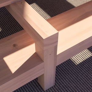K&ouml;nnte beinhalten: Nahaufnahme einer Holzbank mit nat&uuml;rlicher Oberfl&auml;che. Die Bank besteht aus mehreren zusammengef&uuml;gten Holzst&uuml;cken. Die Bank steht auf einem gemusterten Teppich.