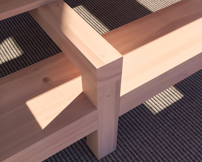 K&ouml;nnte beinhalten: Nahaufnahme einer Holzbank mit nat&uuml;rlicher Oberfl&auml;che. Die Bank besteht aus mehreren zusammengef&uuml;gten Holzst&uuml;cken. Die Bank steht auf einem gemusterten Teppich.