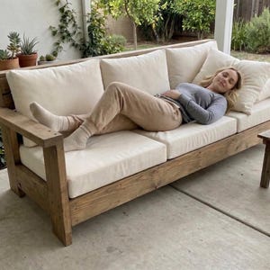 May include: A white ceramic mug with a black handle and the text "But First, Coffee" in a bold, black font. The mug is set against a blurred background, highlighting its simple design.