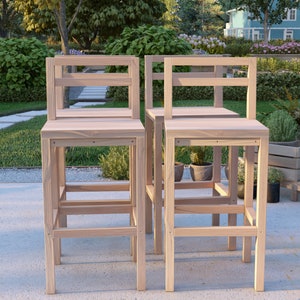 Puede incluir: Dos taburetes de bar de madera sin terminar con un dise&ntilde;o sencillo. Los taburetes tienen un asiento rectangular y un respaldo con una sola barra horizontal.
