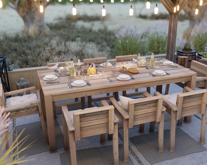 Op de afbeelding: Een houten eettafel voor buiten met zes stoelen, gedekt voor een maaltijd met borden, bestek en glazen. De tafel is gemaakt van natuurlijk hout en heeft een rustieke uitstraling. De stoelen zijn ook van hout en hebben kussens.