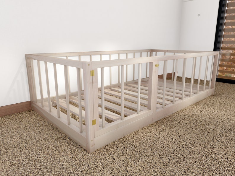 May include: A white wooden crib with a slatted design and a hinged door. The crib is on a beige carpet.
