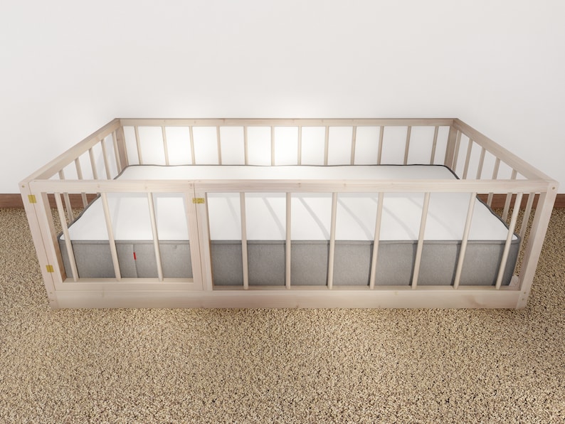May include: A wooden crib with a gray mattress and a white sheet. The crib has a wooden frame with slats and a removable side panel.